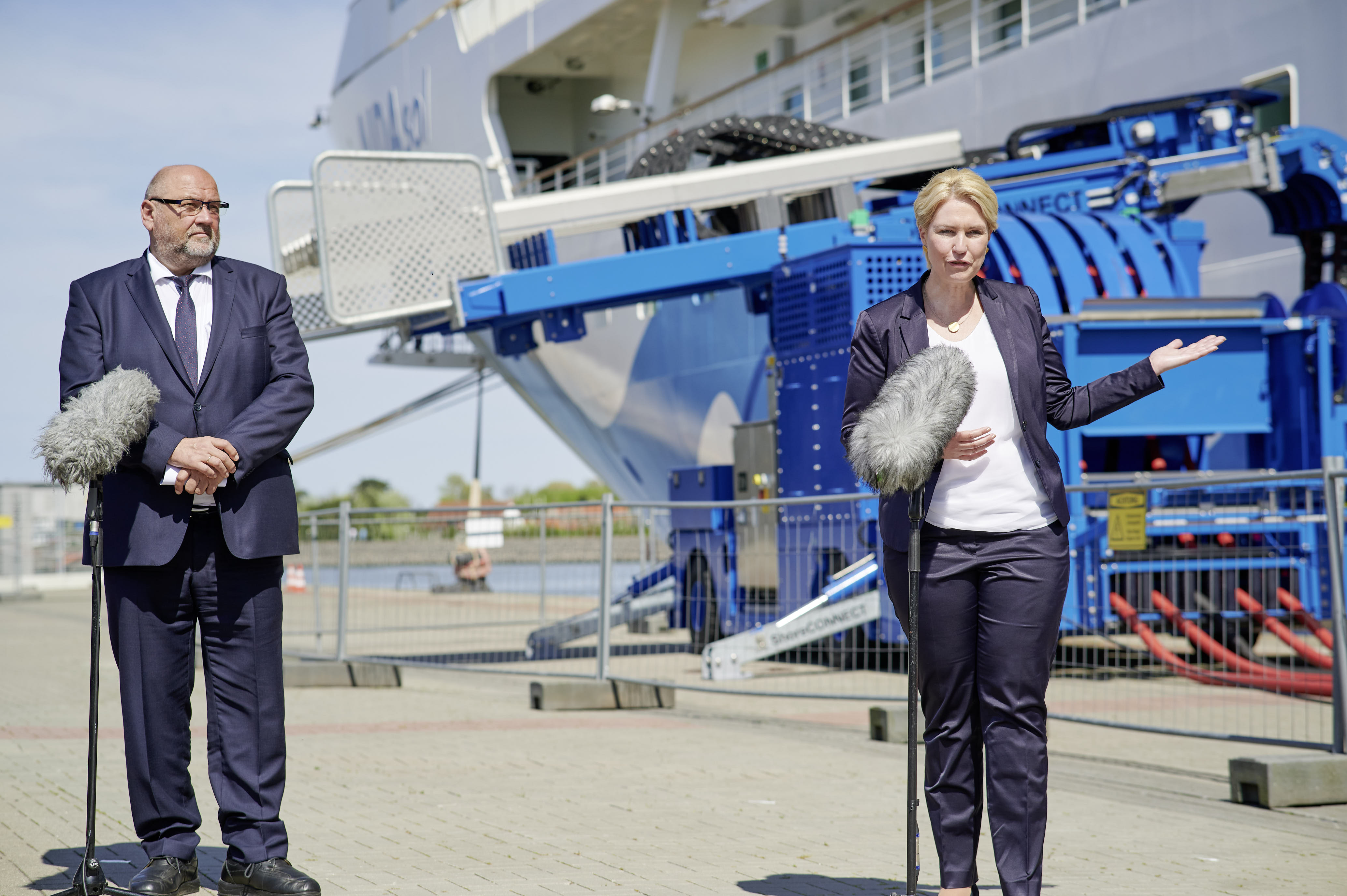 Im Vordergrund zwei Personen. Im Hintergrund Landstromwagen und Schiff