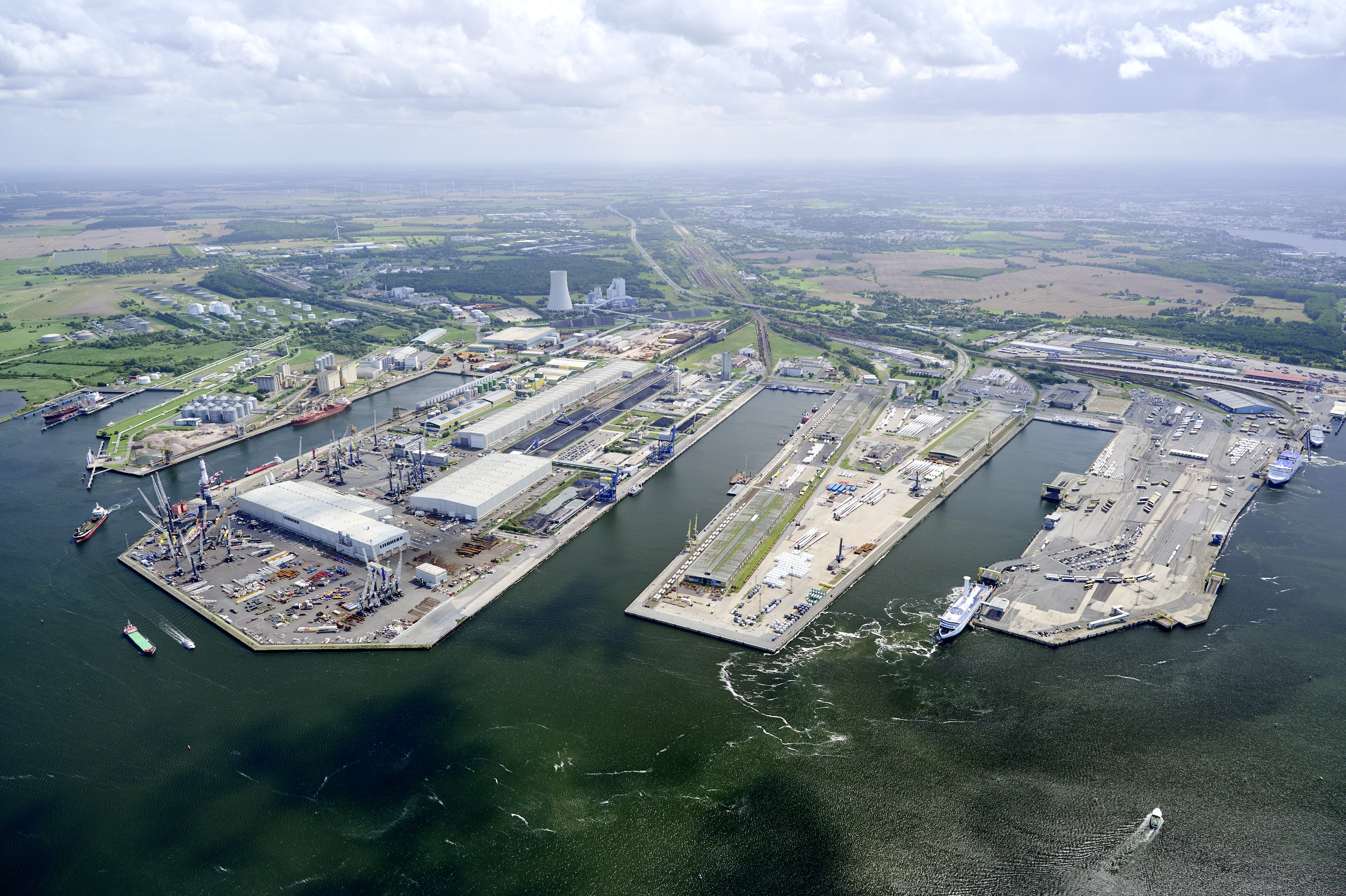 Aerial view of the Port of Rostock with quays, industrial and logistics areas, and ships in the harbor basin.