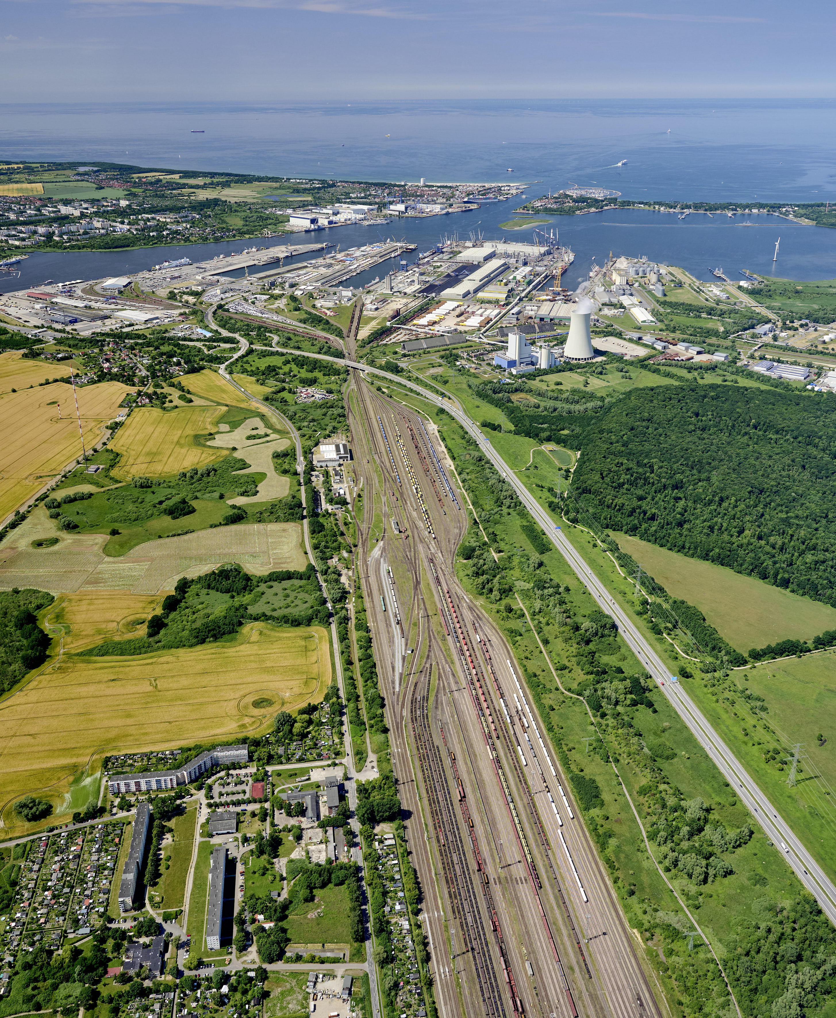 Luftaufnahme der Hinterlandanbindung des Seehafens Rostock. Zu sehen sind der Rangierbahnhof Seehafen Rostock, die Autobahnanbindung sowie im Hintergrund der Seehafen Rostock.