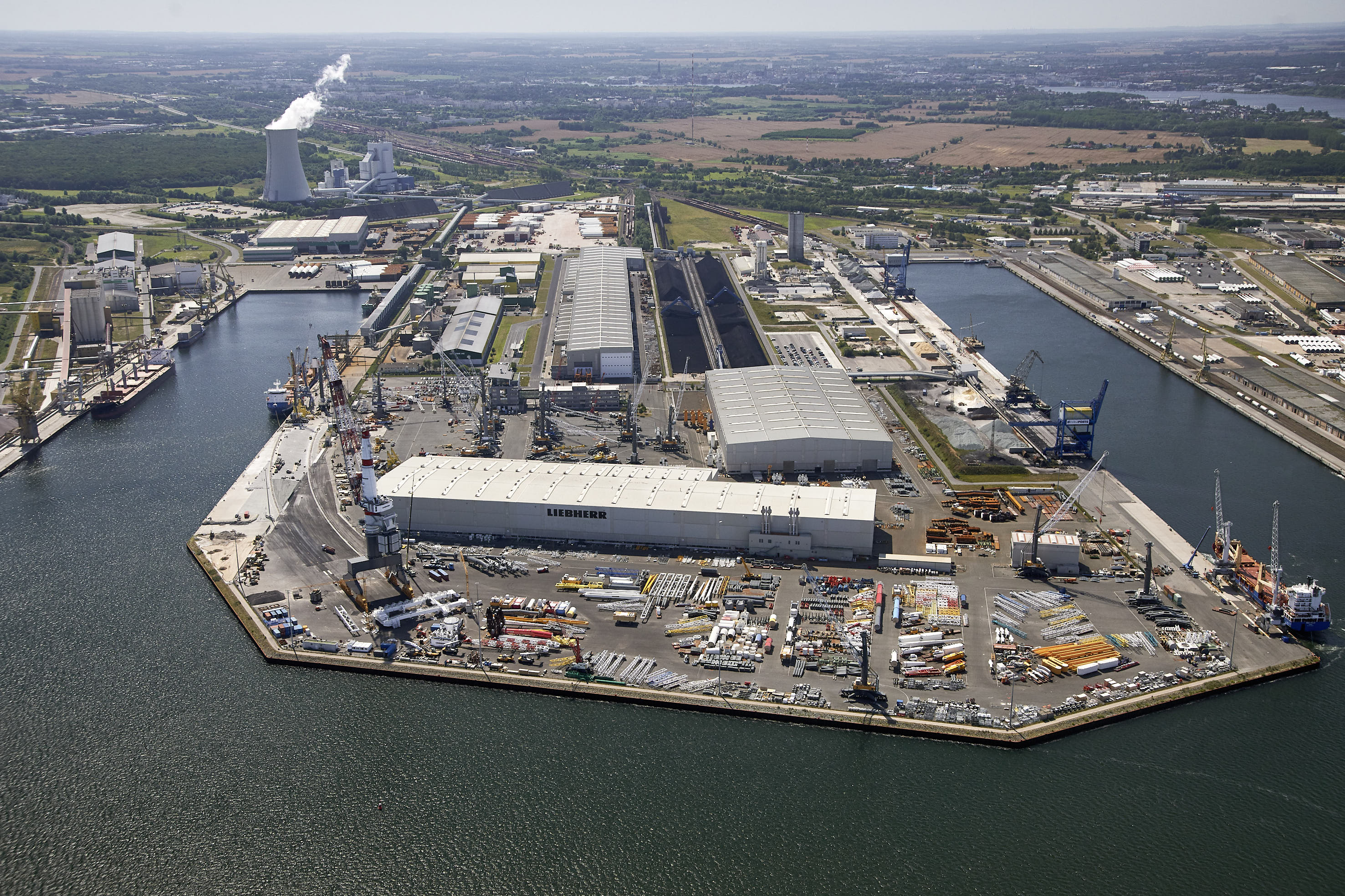 Luftaufnahme des Betriebsgeländes von Liebherr Rostock. Detailaufnahme mehrerer mobiler Hafenkrane auf einer Lagerfläche.