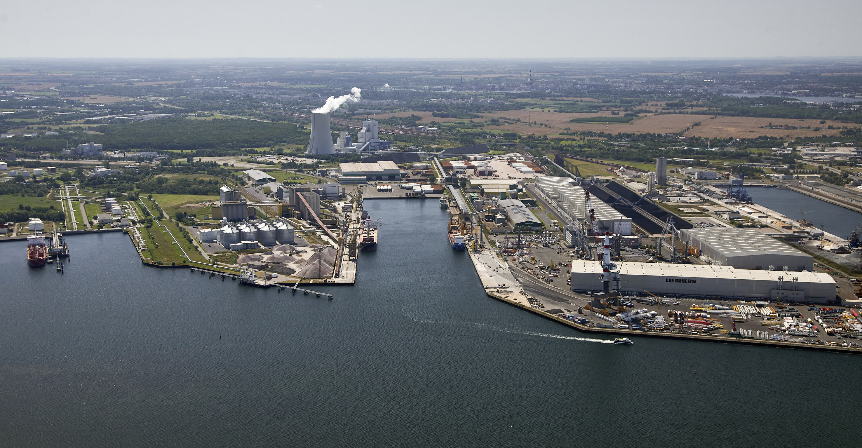 Aerial view of the Port of Rostock with quays, industrial and logistics areas, and ships in the harbor basin.