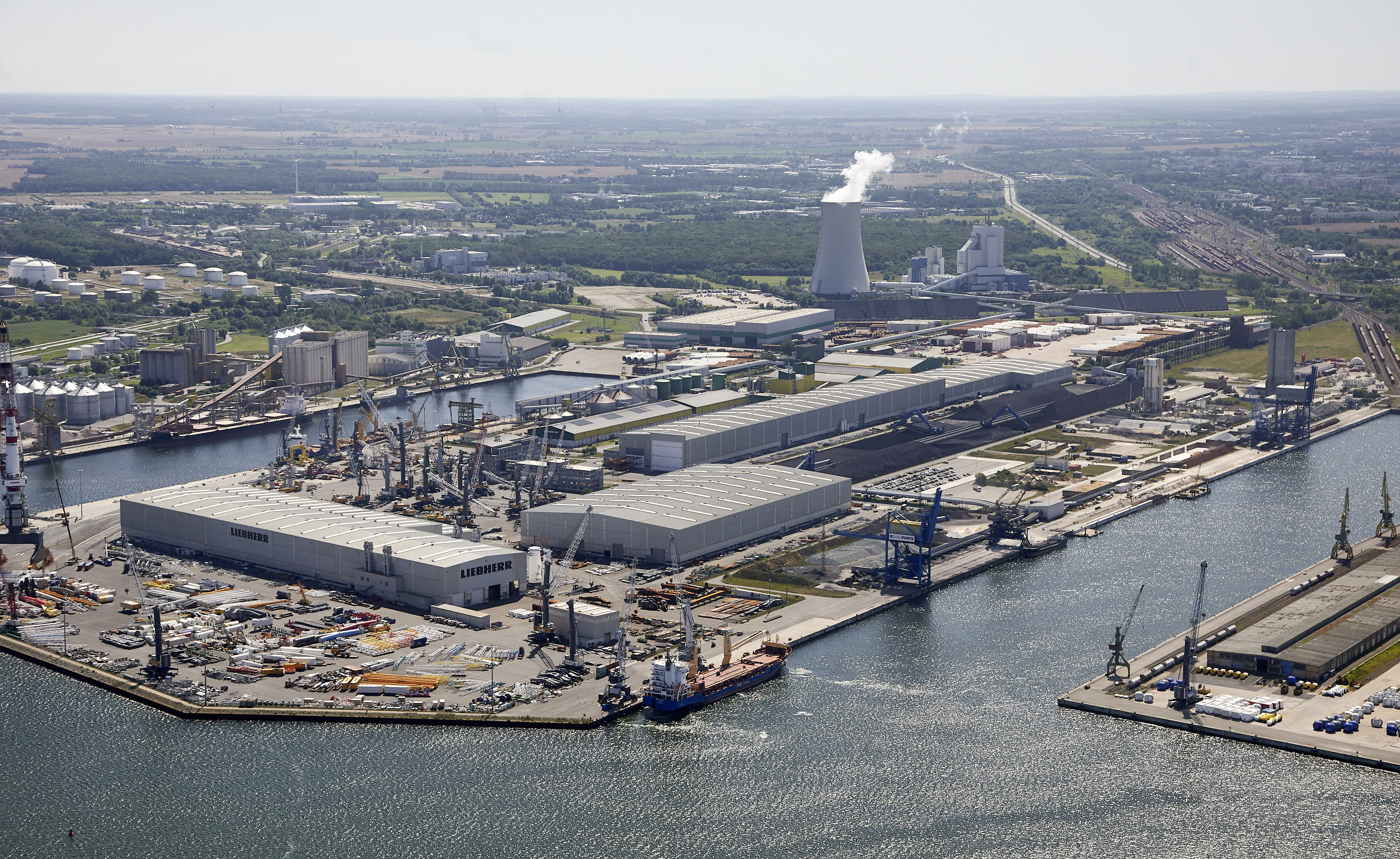 Luftaufnahme des Betriebsgeländes von Liebherr Rostock. Detailaufnahme mehrerer mobiler Hafenkrane auf einer Lagerfläche.