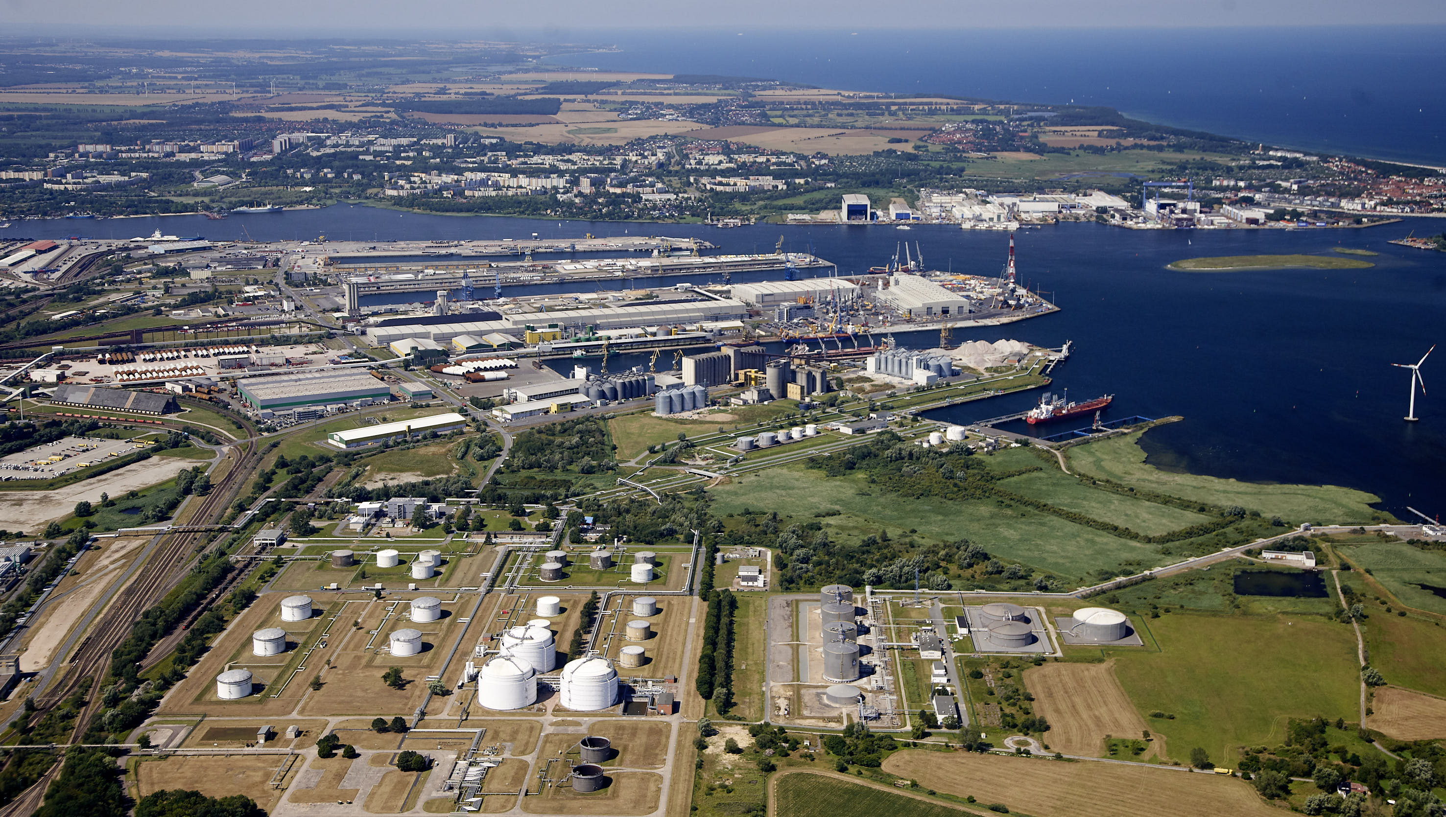 Luftaufnahme des Überseehafens Rostock mit Kaianlagen, Industrie- und Logistikflächen sowie Schiffen im Hafenbecken.