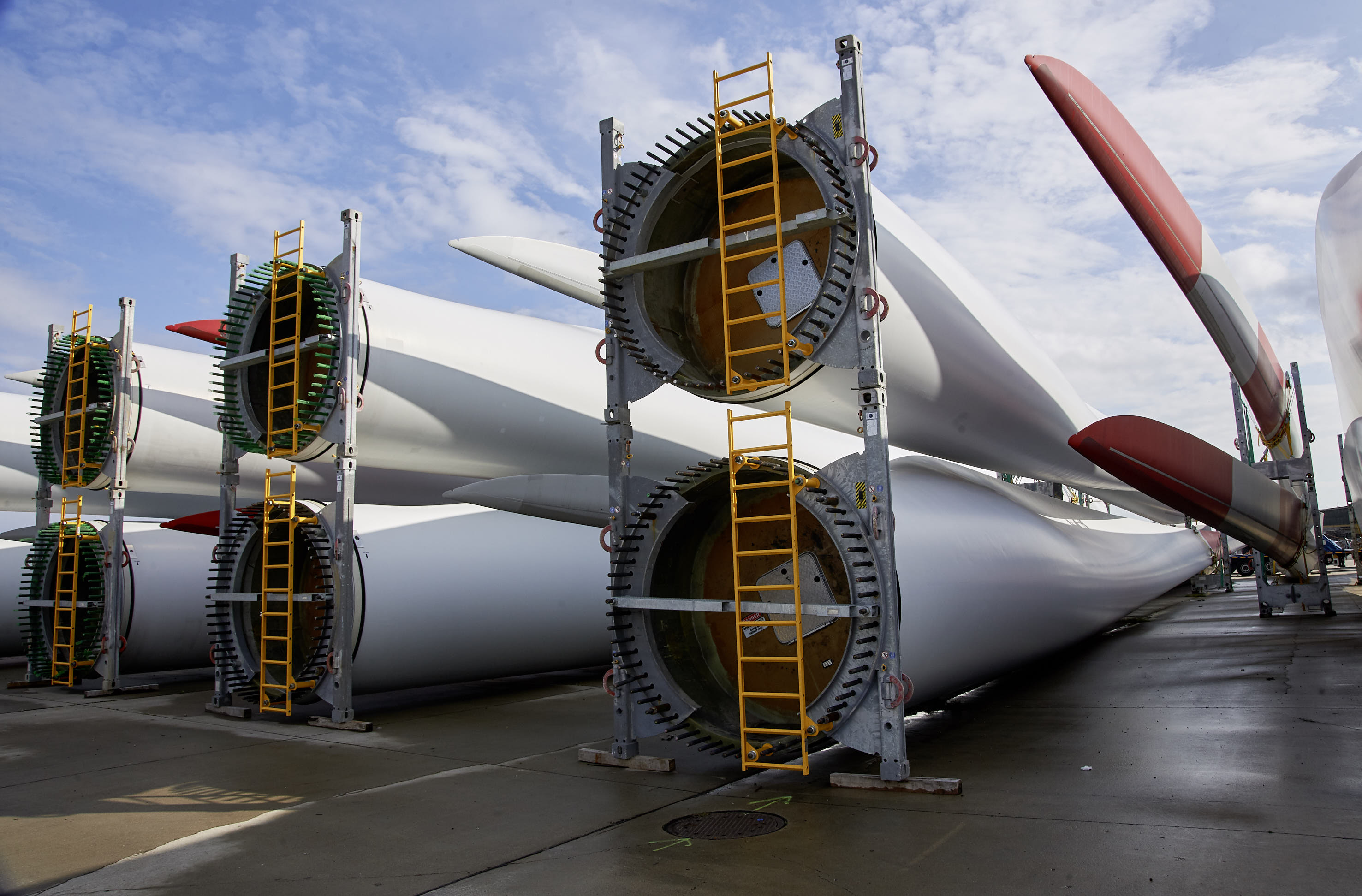 Mehrere riesige Rotorblätter für Windkraftanlagen liegen auf dem Hafengelände.