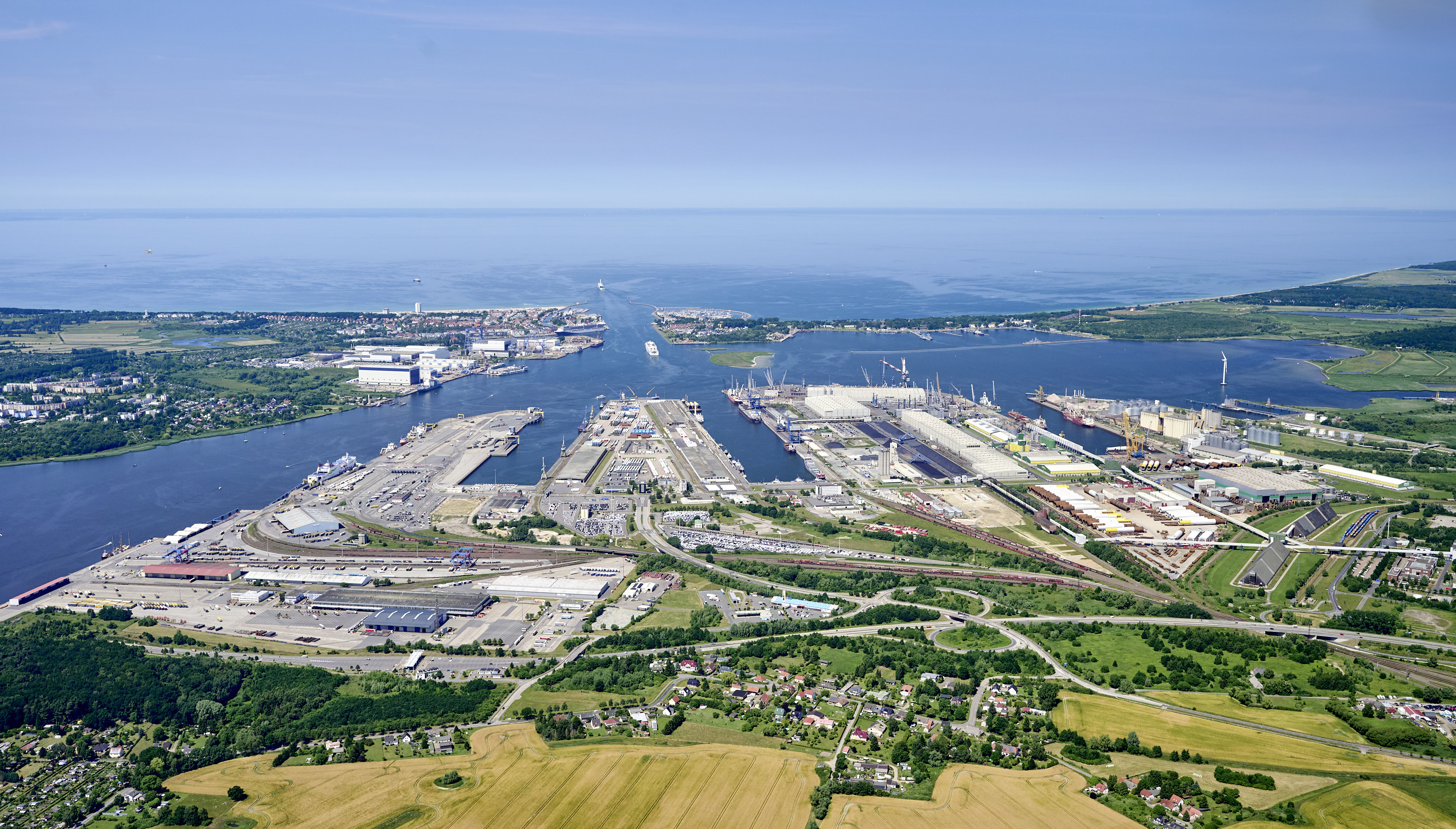 Luftaufnahme des Überseehafens Rostock mit Kaianlagen, Industrie- und Logistikflächen sowie Schiffen im Hafenbecken.