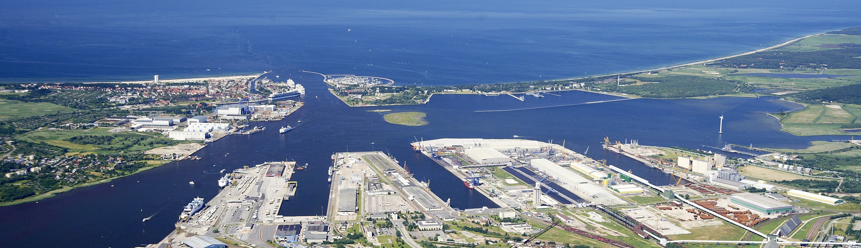 Luftbild des Kreuzfahrthafens Warnemünde aus dem Jahr 2006. Ein Kreuzfahrtschiff liegt an Liegeplatz 7, während die AIDAcara Liegeplatz 8 anläuft. Auf der gegenüberliegenden Seite der Warnow befindet sich das Hotel Yachthafenresidenz in Hohe Düne.